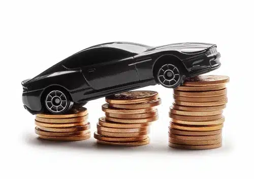 A black toy car balanced on stacked coins.