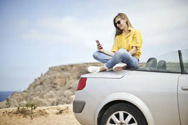 women sits on car and googles different types of car insurance