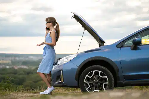 women upset on the phone alongside broken down car