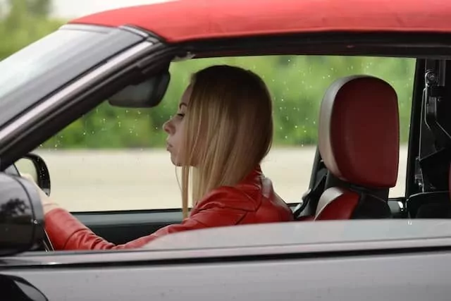 Woman in red leather jacket driving a red car