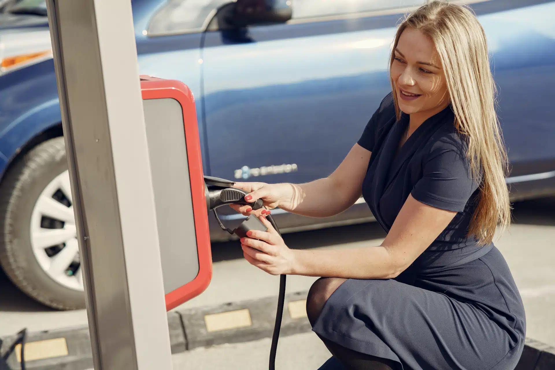 This blonde Australian lady charges her electric car so she has a lower carbon footprint.