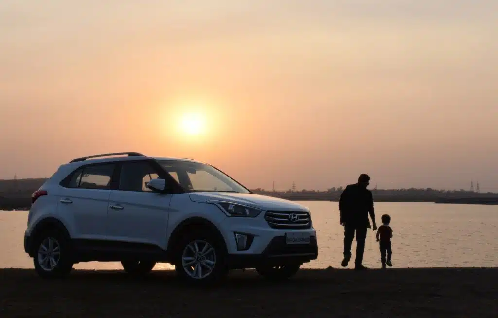 man stands with his son alongside their car looking at the sunset and feeling secure about the driving holiday because he has car insurance 