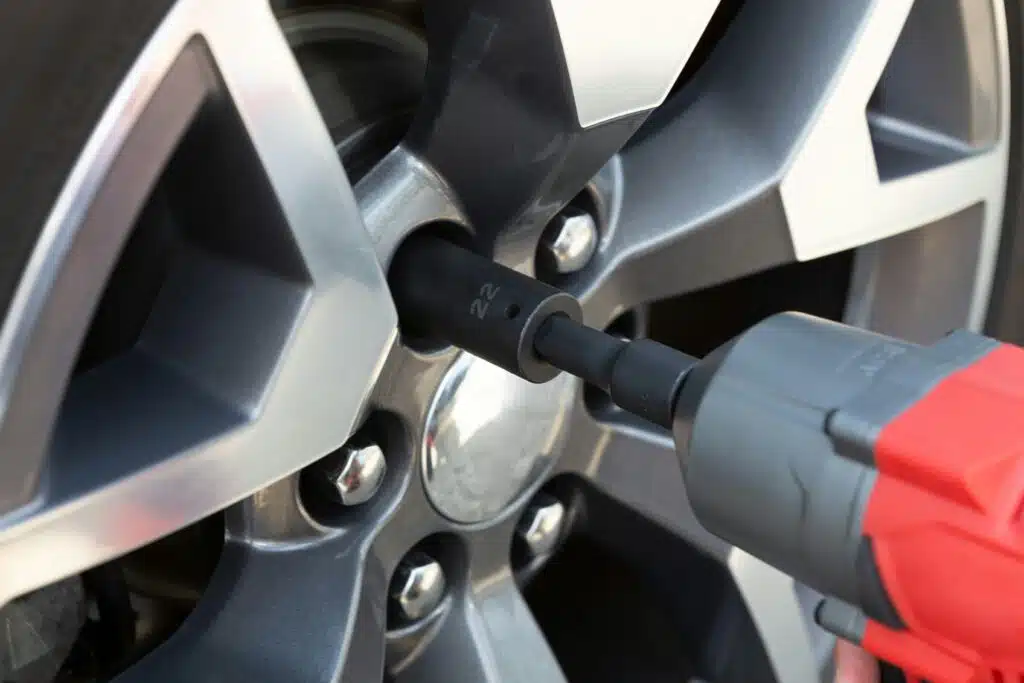 An impact wrench is skillfully used to tighten or loosen the lug nuts on a car wheel, a crucial step in car servicing. Remember, regular maintenance ensures optimal performance, so check how often you should service your car for lasting reliability.