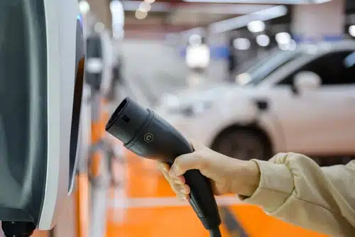 A person plugs a zero emissions vehicle charger into a charging station inside an underground parking lot