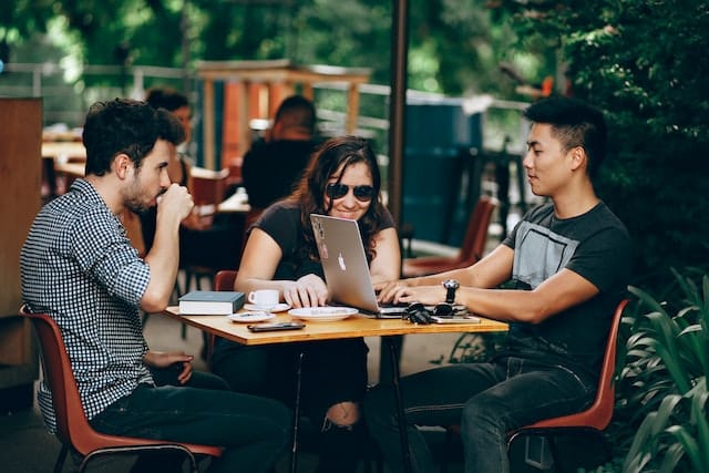 three friends at a coffee shop look at some of the best apps for freelancers they will need to start their business 