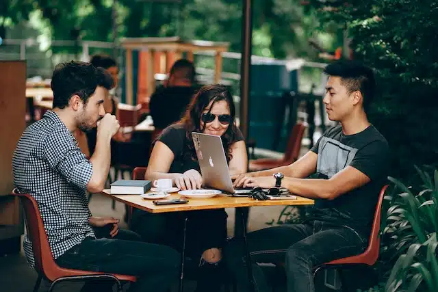 three friends at a coffee shop look at some of the best apps for freelancers they will need to start their business