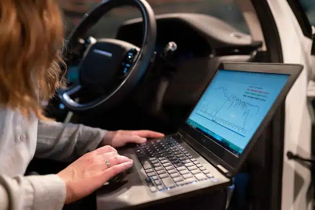 a woman works from her car using her laptop
