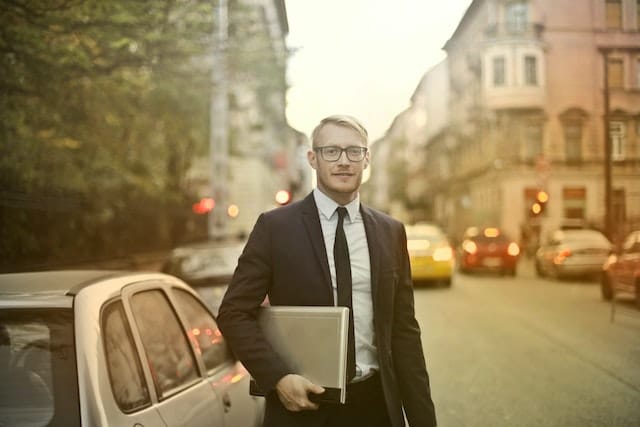 a freelancer has just parked his car and is heading to a meeting with his laptop
