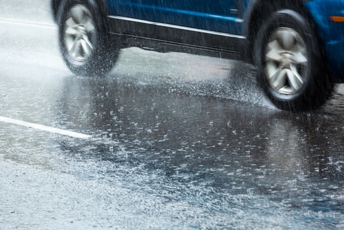 close up of black car wheels driving on wet road