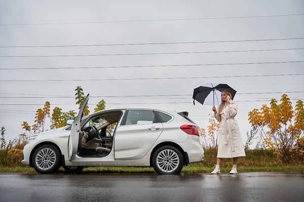 "A white car with a punctured tire stranded on the roadside, emphasizing the need for Comprehensive Car Insurance in Australia to cover unexpected incidents like this."