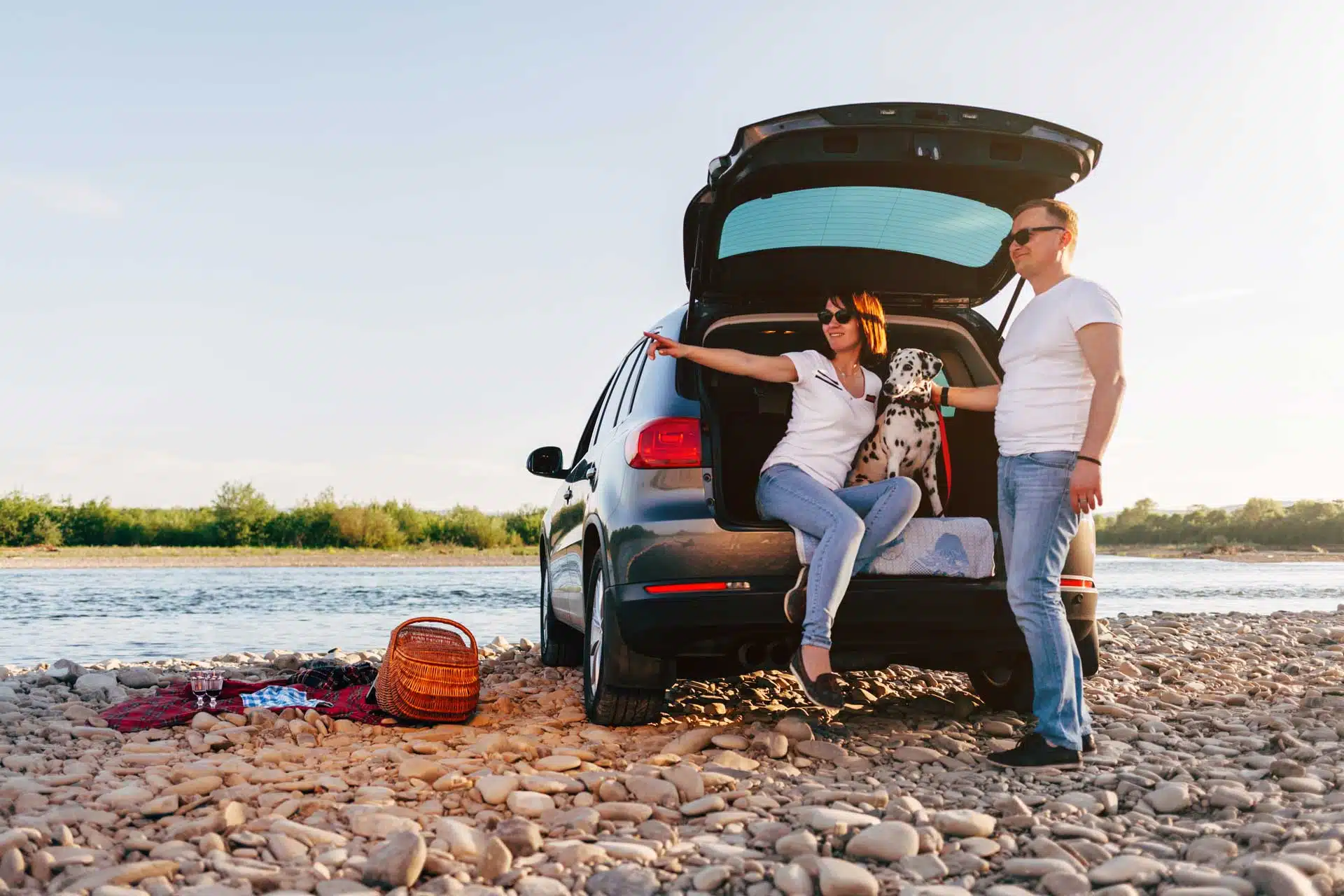 This happy couple enjoys the beach after feeding their dog water from a pet travel water bottle.