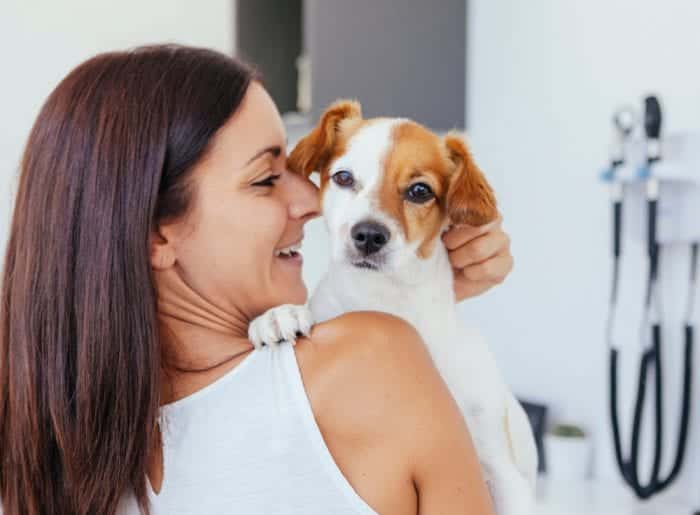 woman holding terrier dog over her right shoulder