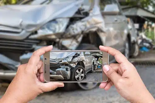 Somebody taking photo of car crash to make claim for car insurance