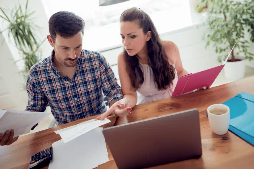 A female and male sitting at a desk in a home going over financial documents together before deciding on car loans and novated leases