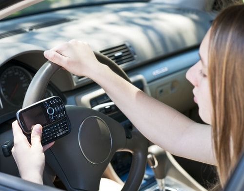 This driver will be denied car insurance cover if she knocks the car ahead while illegally using her phone and driving.