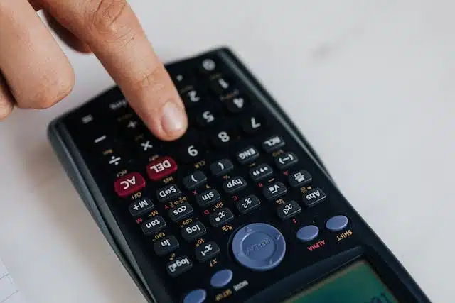A person is using a calculator on a desk to choose their excess.