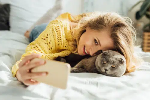 woman in yellow taking selfie with cats for Instagram