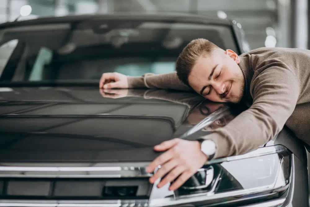 man hugging new car