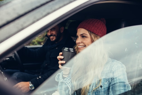 this woman is prepared for winter with her car drinking coffee in the passenger seat while going of the best electric car through a roundabout