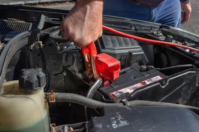 Connecting jumper cables to jump start a car. 