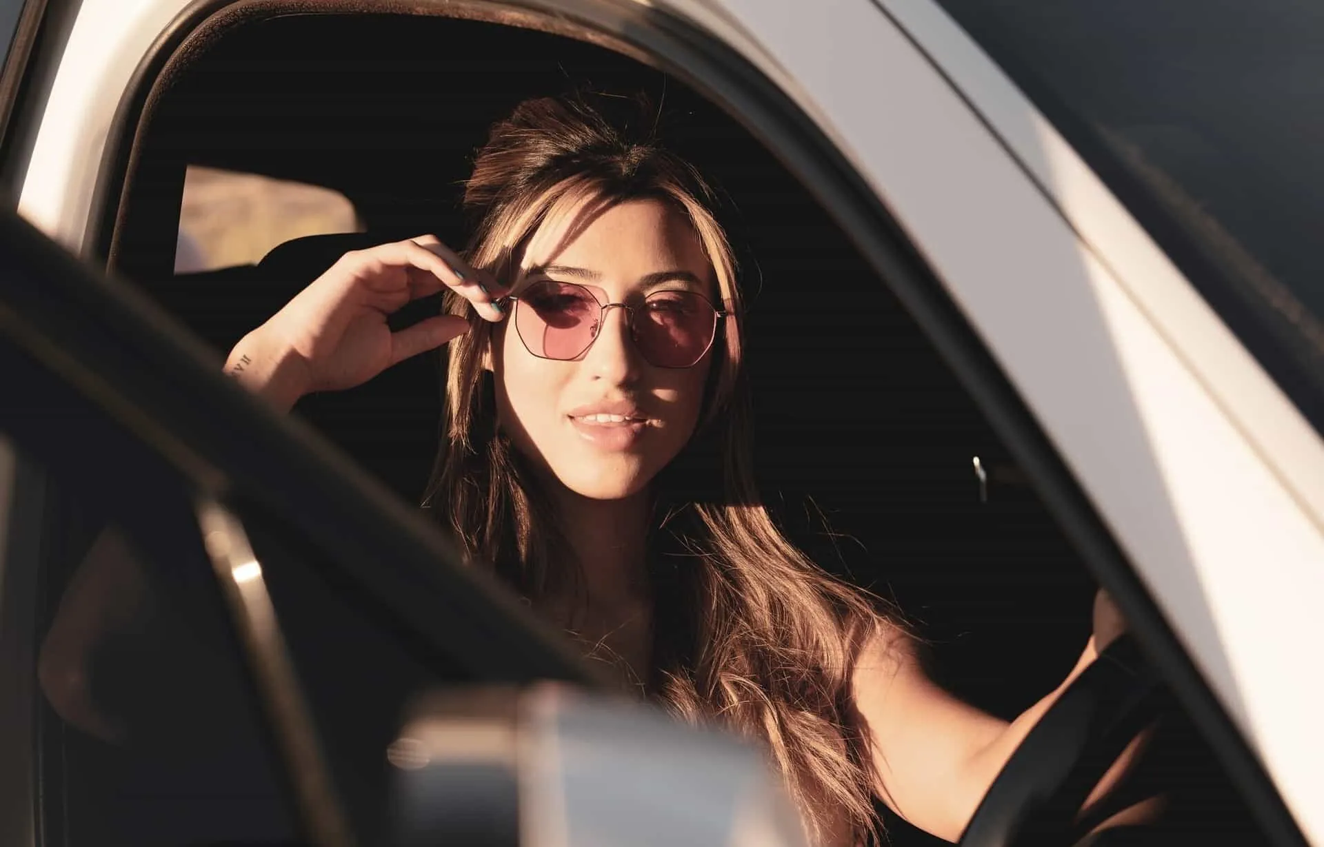 A woman wearing sunglasses in a car with advanced safety features.