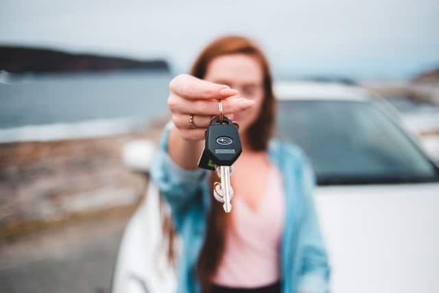 This woman is holding her car keys after buying a new subaru car