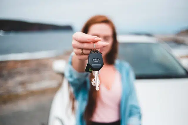 This woman is holding her car keys after buying a new subaru car 