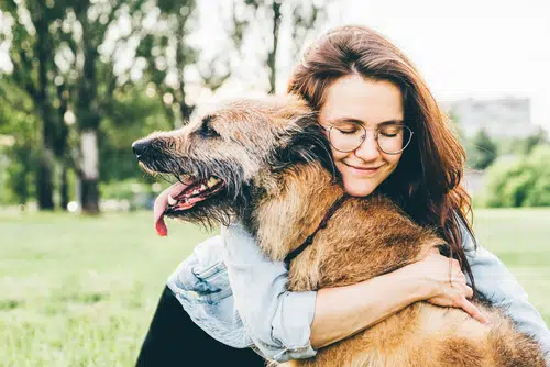woman hugging older dog outside. dog loves his owner. This dog's pet parent may be aware of the 333 rule for dogs 