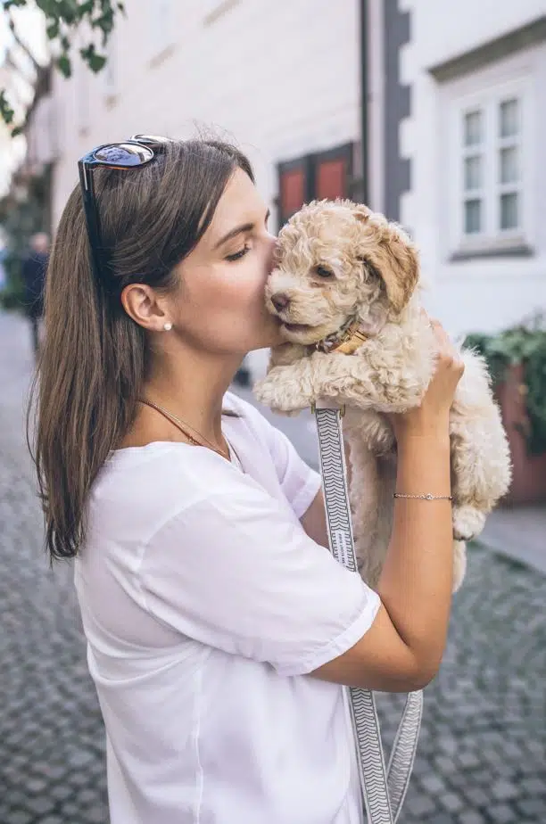 woman kissing blonde puppy crying