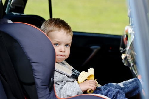 toddler kid in car having banana for snack