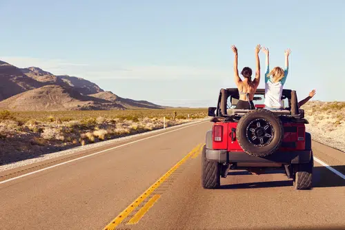 four young people in jeep for summer driving trip. servicing your car before a road trip is important for road safety