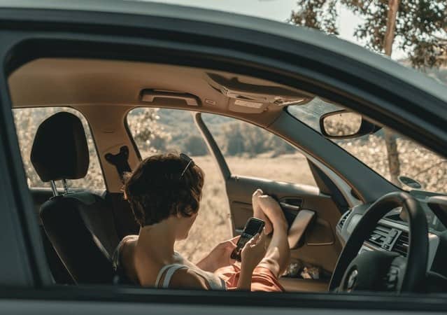 woman avoids distracted driving by pulling over to check phone