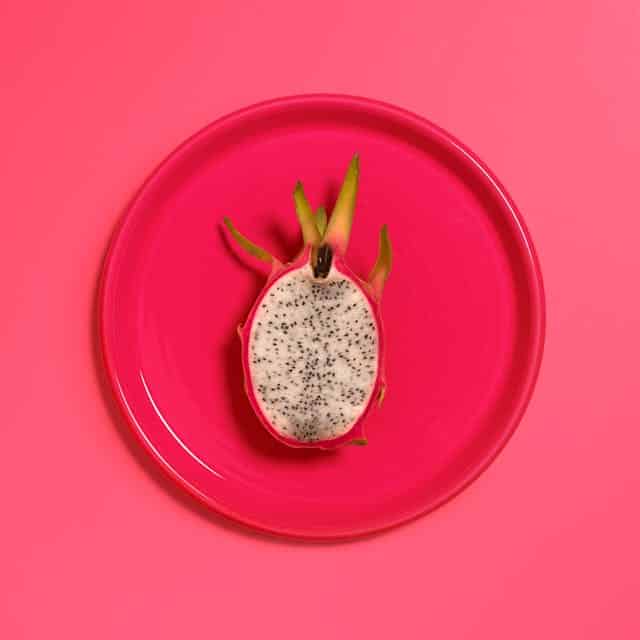 Half of a dragon fruit sits on a plate, ready to be enjoyed.