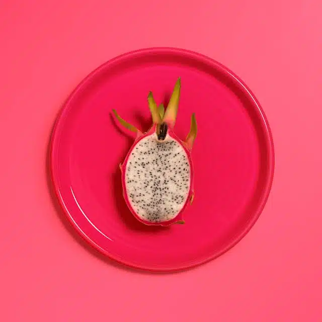 Half of a dragon fruit sits on a plate, ready to be enjoyed.
