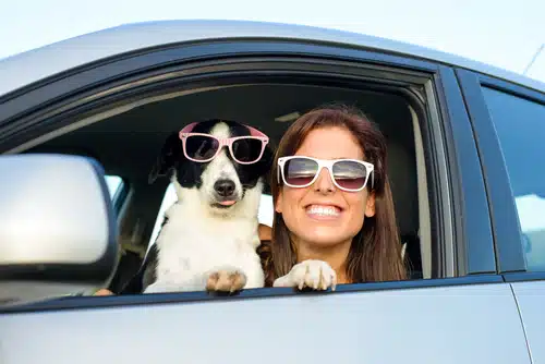 A woman and her dog enjoying a dog friendly travel adventure in a car.