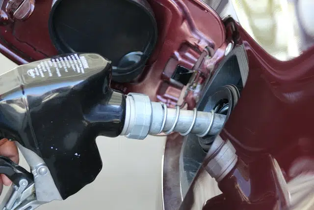 close up of a petrol pump putting petrol into a red car 