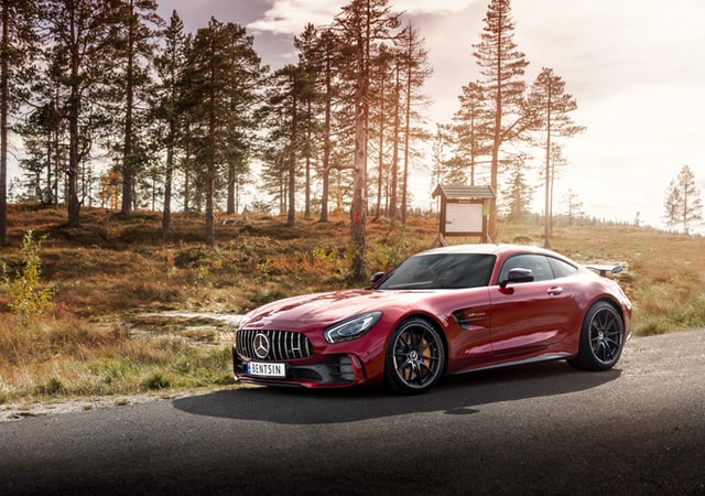 red mercedes supercar on road near forest. Super cars are almost always petrol engines