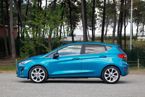 bright blue ford fiesta parked on road in front of trees. the ford fiesta ecoboost is one of australia's most fuel efficient cars
