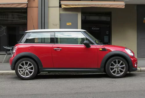 red mini cooper parked on side of street outside shops