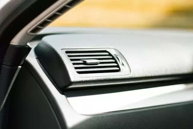 Close-up of a car’s dashboard showing an air vent with a horizontal vent control lever, highlighting areas where odors can linger—perfect for addressing how to get wet smell out of your car.