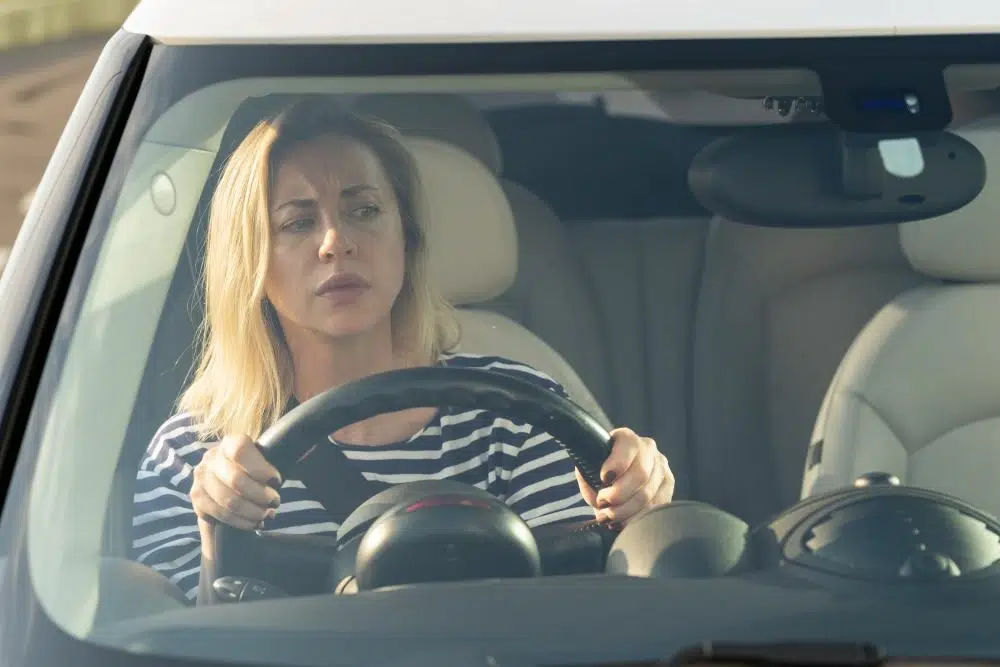 woman suspects she is being followed by a car while driving while approaching roundabout looking in mirror