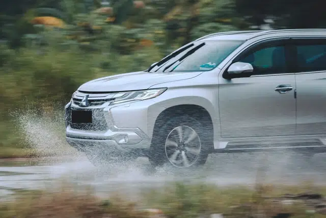 silver SUV car driving through water on road