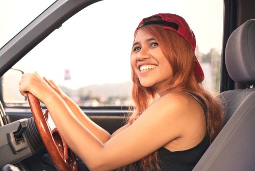 Young asian woman with long hair in car behind drivers wheel