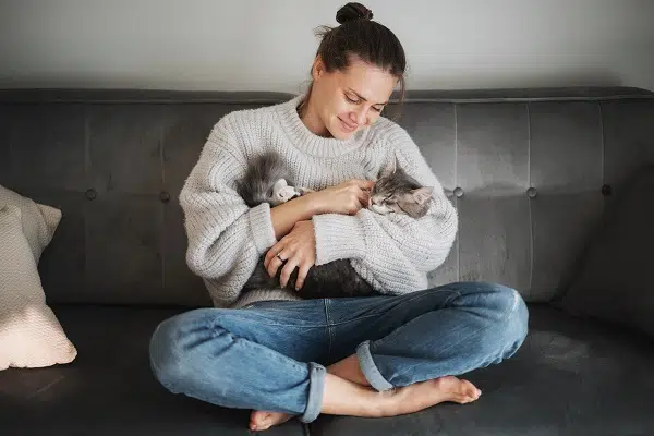 this woman is thinking about pet insurance vs savings while cuddling her cat