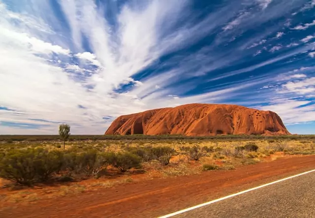 This picture shows the natural wonder Uluru, perfect for a family road trip during a school break.