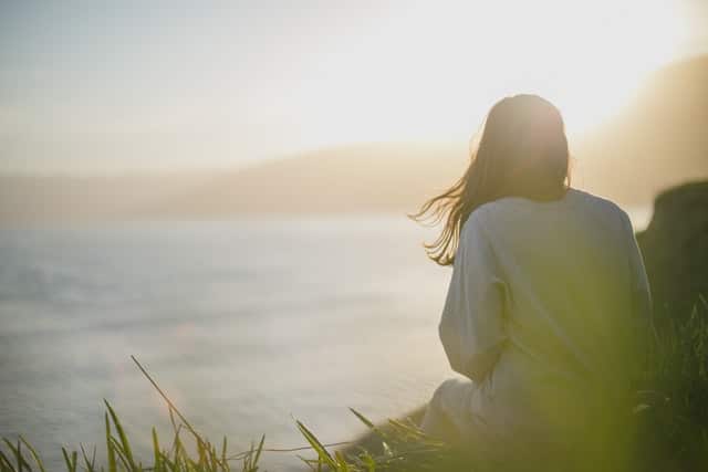 this woman sitting on a hill looking at the ocean has just had to buy car tyres