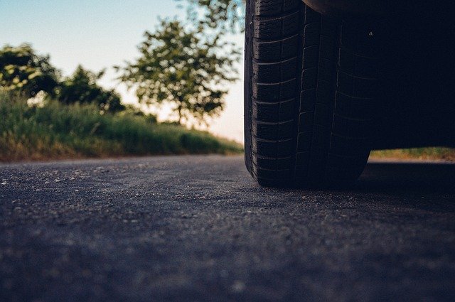 close up of left hand front car tyres on asphalt road