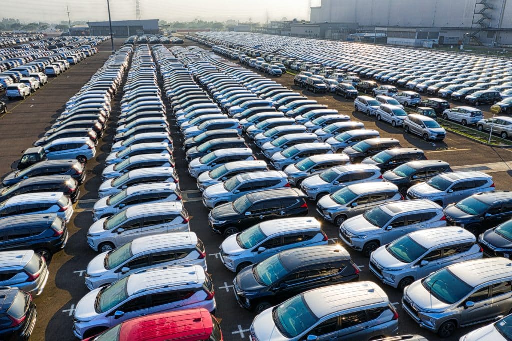 The picture shows thousands of new cars parked in a massive parking lot. People may be buying cars at auction 