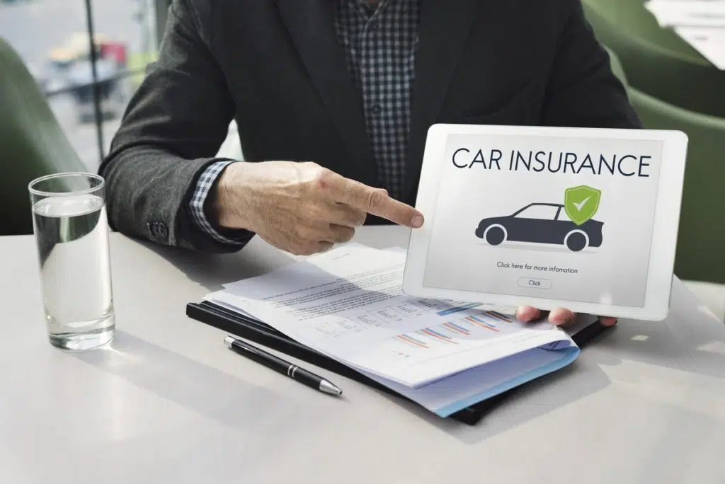 A man points at a tablet that says 'car insurance'. He may be explaining how to compare car insurance to find the best car insurance deal for you