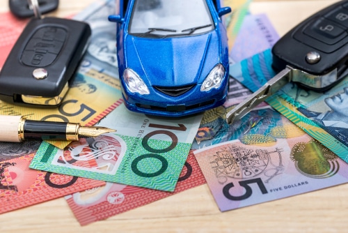 Australian dollar notes with car keys and a toy car. buying cars at auction can save you money